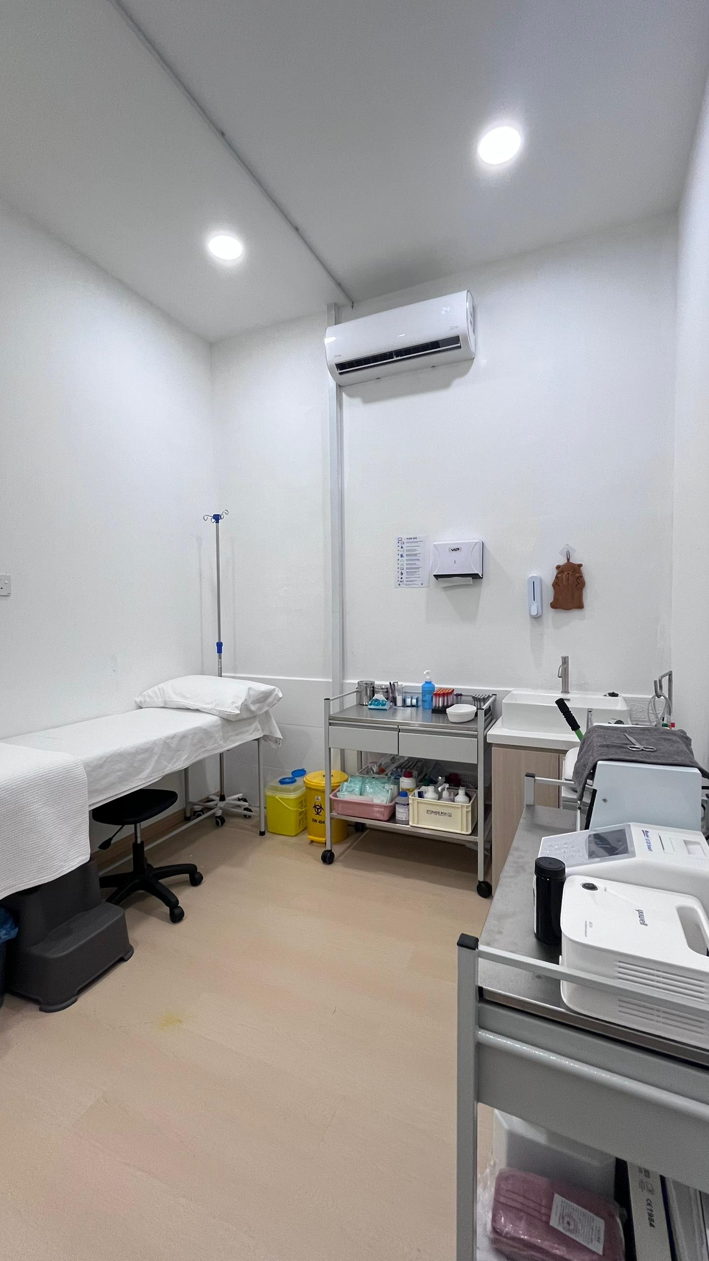 Treatment room with examination bed and IV drip stand at OneHealth Clinic Pontian